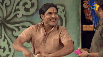 A Man In A Wig Is Laughing While Another Man Holds A Pink Object In His Hand GIF