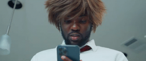 A Man In A Wig Is Looking At His Phone . GIF