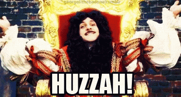 A Man In A Wig Is Sitting In A Chair With The Words Huzzah Written On The Bottom GIF