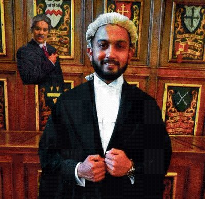 A Man In A Wig Is Standing In Front Of A Coat Of Arms GIF