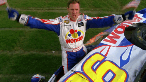 A Man In A Wonder Racing Suit Is Standing Next To A Car GIF