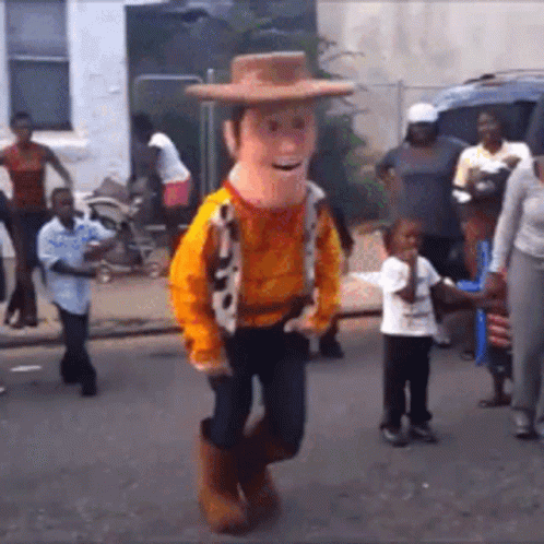 A Man In A Woody Costume Is Dancing On The Street GIF
