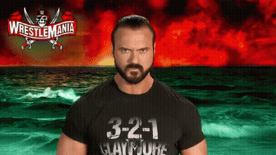 A Man In A Wrestlemania Shirt Stands In Front Of A Ocean GIF