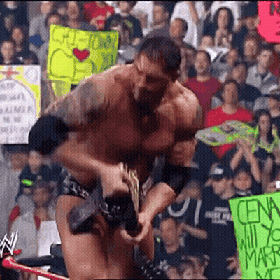 A Man In A Wrestling Match Is Holding A Sign That Says ' Cena ' On It . GIF