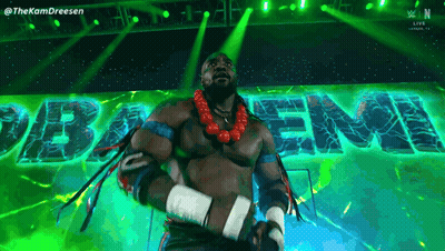 A Man In A Wrestling Outfit Is Standing In Front Of A Green Sign That Says " Baem " GIF