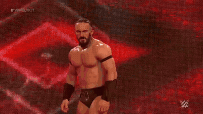 A Man In A Wrestling Outfit Is Walking On A Stage With A Red Background . GIF