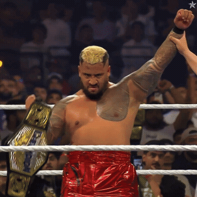 A Man In A Wrestling Ring Holds Up A Belt That Says World Heavyweight Champion GIF