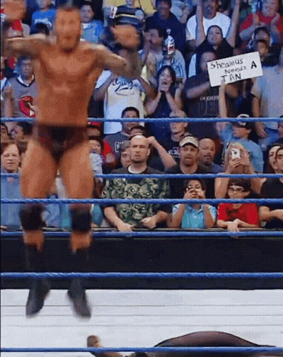 A Man In A Wrestling Ring Holds Up A Sign That Says ' Shawnus ' GIF