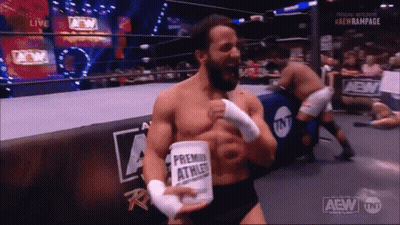 A Man In A Wrestling Ring Is Holding A Can That Says ' Premier Athlete ' On It GIF