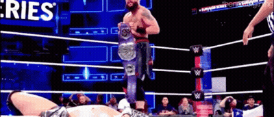 A Man In A Wrestling Ring Is Holding A Championship Belt . GIF