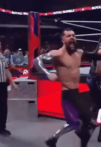 A Man In A Wrestling Ring With A Referee And A Sign That Says Royal Rumble On It GIF