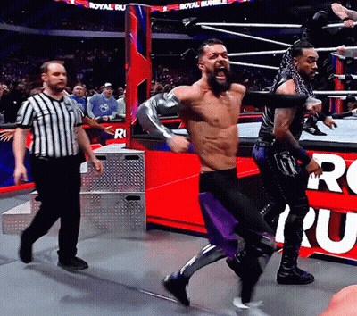 A Man In A Wrestling Ring With A Referee And A Sign That Says Royal Rumble On It GIF