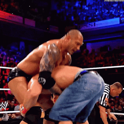 A Man In A Wrestling Ring With A Referee That Says ' Ric ' On His Shorts GIF