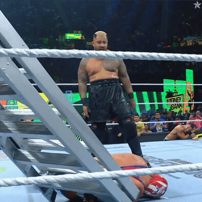 A Man In A Wrestling Ring With A Sign That Says Money Bank In The Background GIF