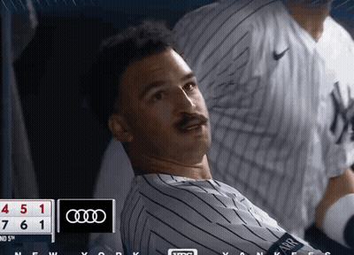 A Man In A Yankees Jersey Is Looking At The Scoreboard GIF