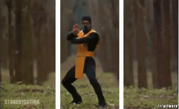 A Man In A Yellow And Black Costume Is Holding A Sword In A Forest . GIF