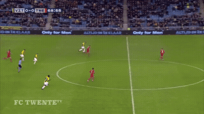 A Man In A Yellow And Black Striped Shirt Is Jumping In The Air In Front Of A Large D GIF