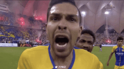 A Man In A Yellow And Blue Jersey Is Screaming At The Camera GIF