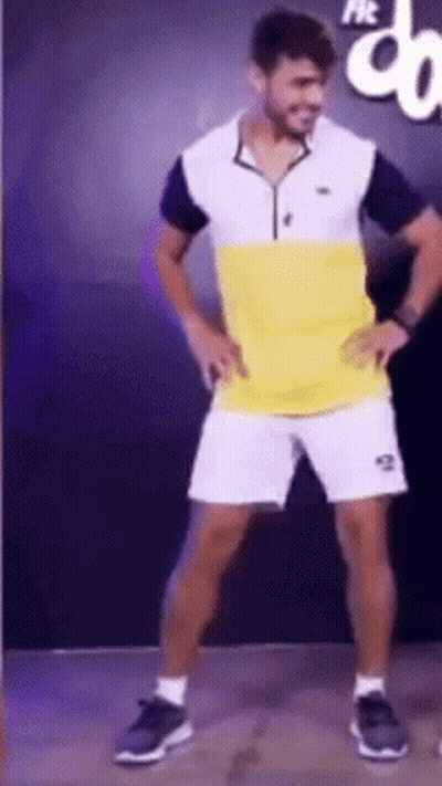 A Man In A Yellow And White Shirt And Shorts Is Dancing GIF