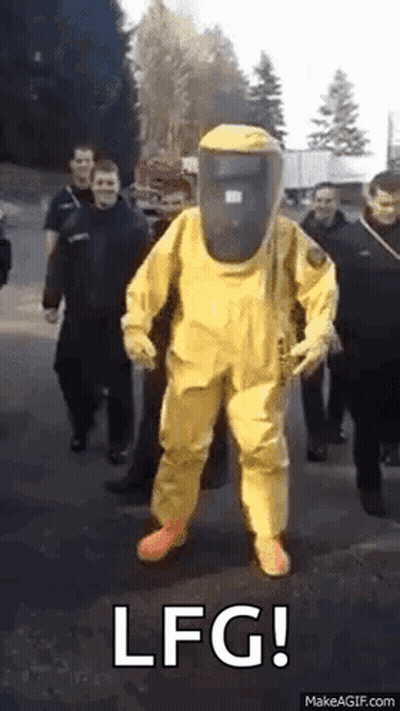 A Man In A Yellow Hazmat Suit Is Standing In Front Of A Group Of People . GIF