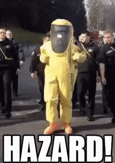 A Man In A Yellow Hazmat Suit Is Walking Down A Street Surrounded By Police Officers .. GIF
