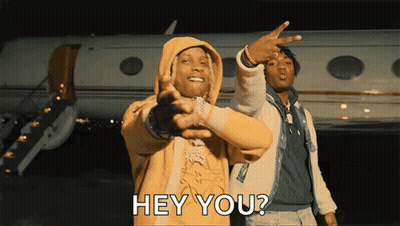 A Man In A Yellow Hoodie Is Pointing At Another Man In Front Of An Airplane And Says Hey You GIF