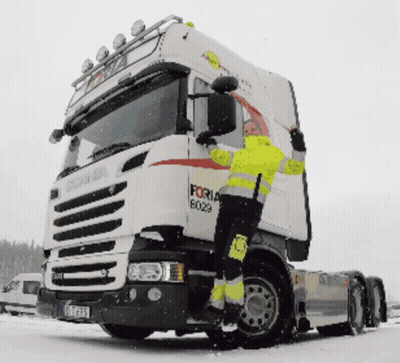 A Man In A Yellow Jacket Climbs Up The Side Of A Forna Truck GIF