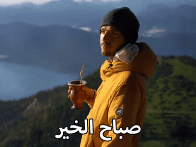 A Man In A Yellow Jacket Is Holding A Cup With A Straw And The Words " صباح الخير " Written On The Bottom GIF