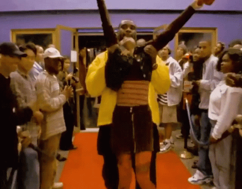 A Man In A Yellow Jacket Is Holding A Woman On His Shoulders GIF