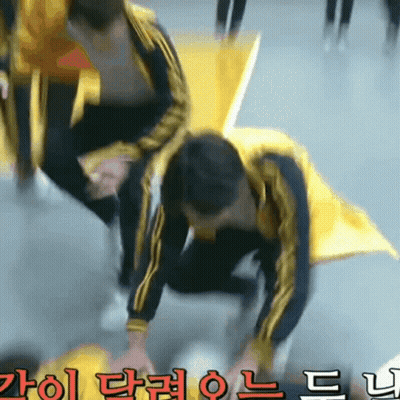 A Man In A Yellow Jacket Is Kneeling Down In Front Of A Sign With Chinese Writing On It GIF