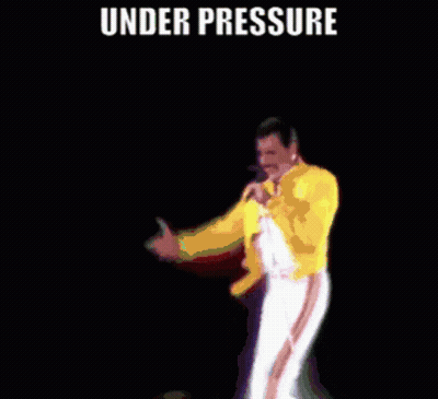 A Man In A Yellow Jacket Is Singing Into A Microphone Under The Words Under Pressure GIF
