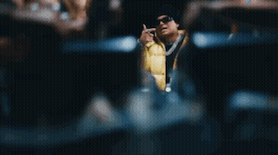 A Man In A Yellow Jacket Is Sitting At A Table With A Bunch Of People Holding Money . GIF