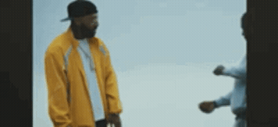 A Man In A Yellow Jacket Is Standing Next To Another Man In A Blue Shirt . GIF