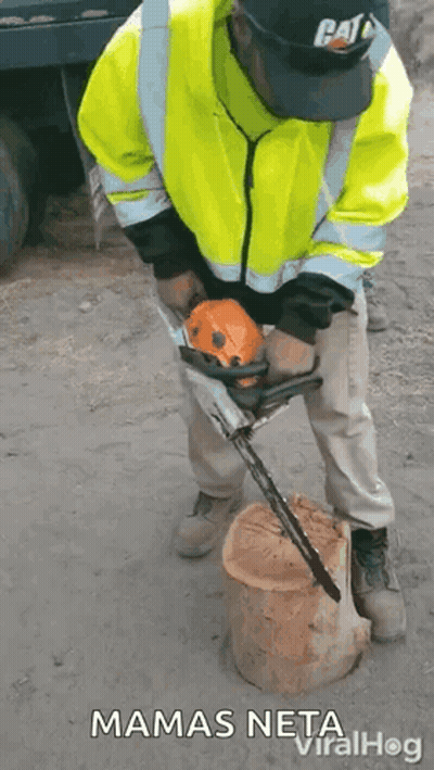 A Man In A Yellow Jacket Is Using A Chainsaw To Cut A Log . GIF