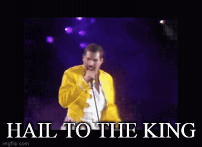 A Man In A Yellow Jacket Singing Into A Microphone With The Words " Hail To The King " Below Him GIF