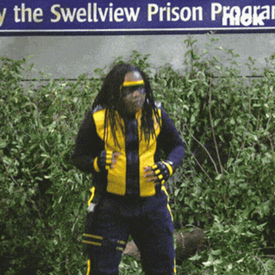 A Man In A Yellow Jacket Stands In Front Of A Sign That Says The Swellview Prison Program GIF