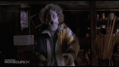 A Man In A Yellow Jacket With A Mask On His Face Is Standing In A Room . GIF