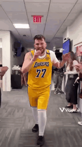 A Man In A Yellow Lakers Jersey Is Dancing In A Hallway . GIF