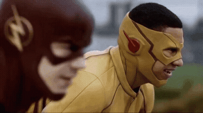 A Man In A Yellow Mask Is Standing Next To Another Man In A Red Mask . GIF