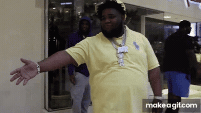 A Man In A Yellow Polo Shirt Is Standing In Front Of A Store Window With His Arms Outstretched . GIF