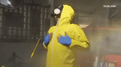 A Man In A Yellow Protective Suit Is Spraying A Car With A Spray Gun . GIF
