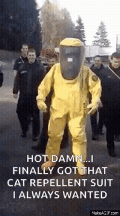 A Man In A Yellow Protective Suit Is Walking Down A Street With A Group Of People . GIF