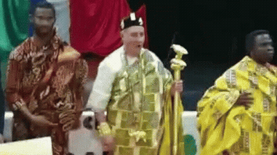 A Man In A Yellow Robe Is Standing Next To Two Other Men In Traditional Clothing . GIF