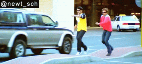 A Man In A Yellow Shirt And A Man In A Red Jacket Are Crossing A Street GIF