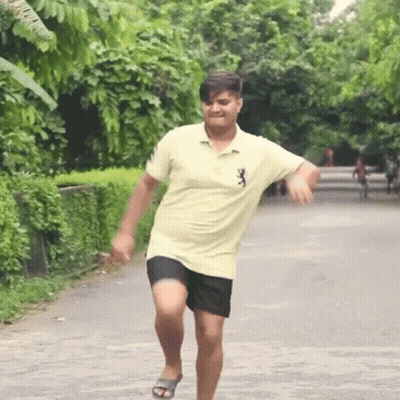 A Man In A Yellow Shirt And Black Shorts Is Running Down The Street GIF