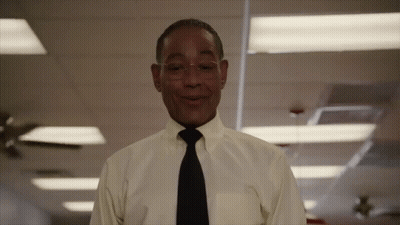 A Man In A Yellow Shirt And Black Tie Smiles GIF