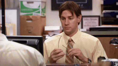 A Man In A Yellow Shirt And Tie Sits At A Desk In Front Of A Computer GIF