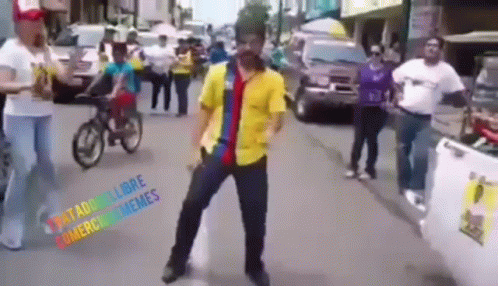 A Man In A Yellow Shirt Is Dancing On A Street GIF