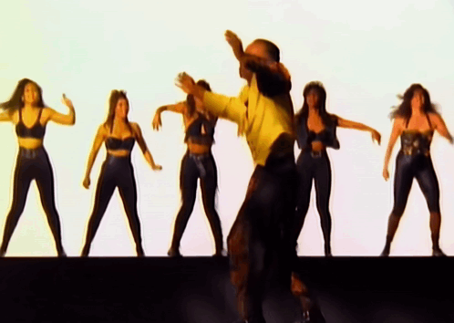 A Man In A Yellow Shirt Is Dancing With A Group Of Women In Black Outfits GIF