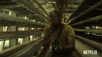 A Man In A Yellow Shirt Is Holding A Gun In A Tunnel With Netflix Written On The Bottom GIF